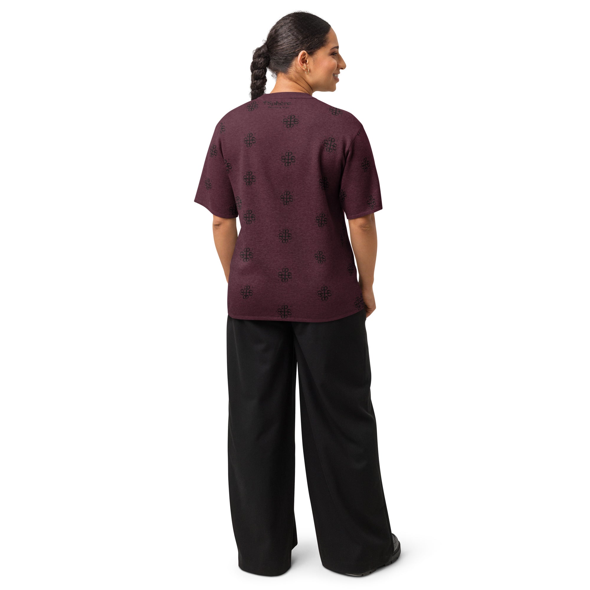 Person wearing a maroon top with black patterns and black pants on a white background